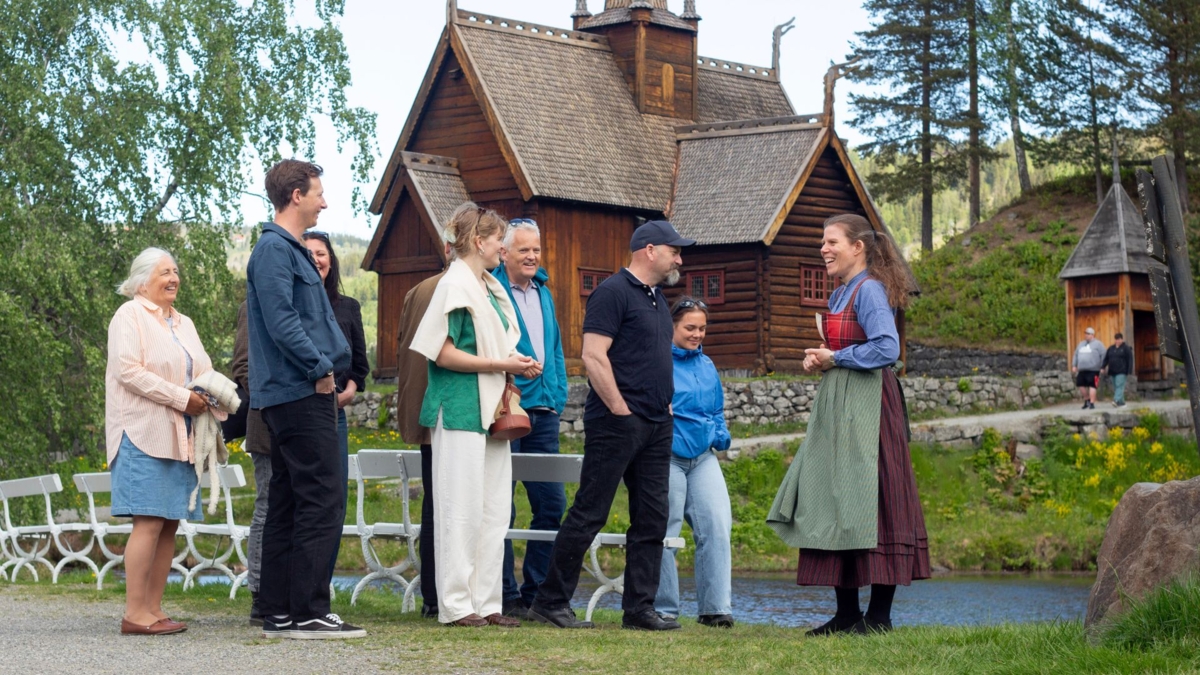 Mennesker foran Garmo-kirka på Maihaugen