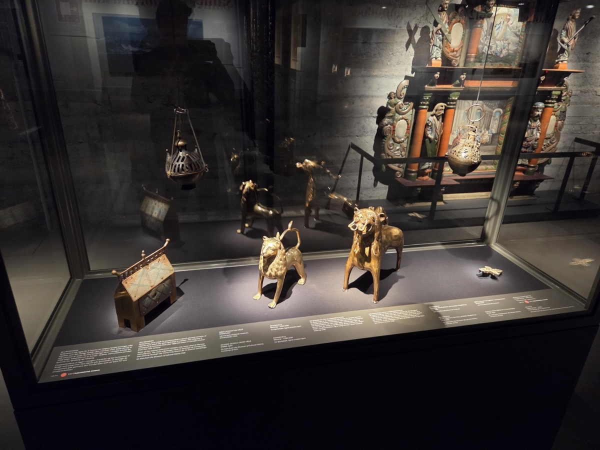 I glassmonteret st&aring;r Hundorpskrinet (1700) med dekorative beslag fra 1200-tallet og to l&oslash;veformede akvamaniler (1200) fra kirker i Gudbrandsdalen. Foto: Maihaugen.

