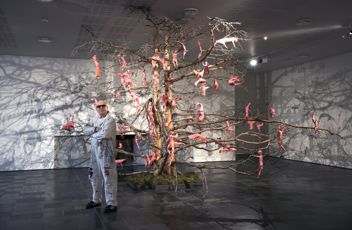 Kjell Erik Killi-Olsen foran en tørr furu dekorert med lyserøde skulpturer.