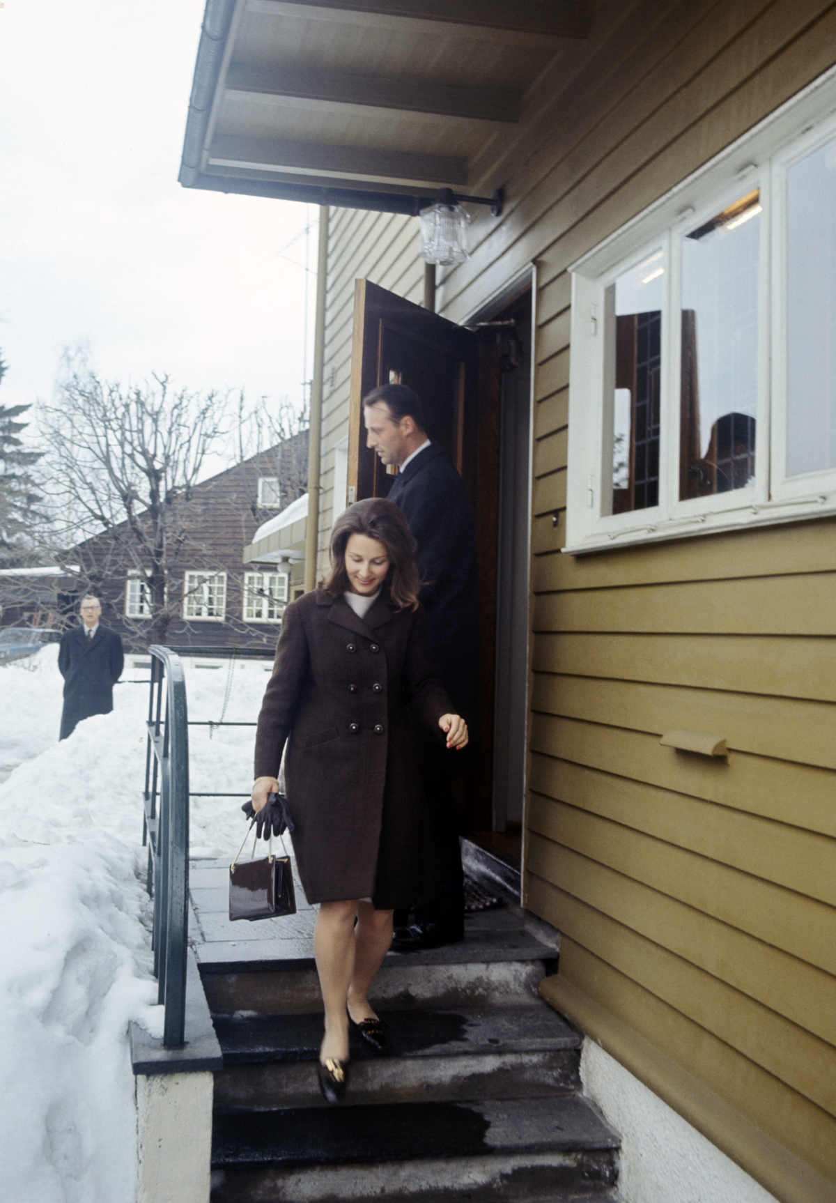 Kronprins Harald og Sonja Haraldsen på trapp utenfor hus.