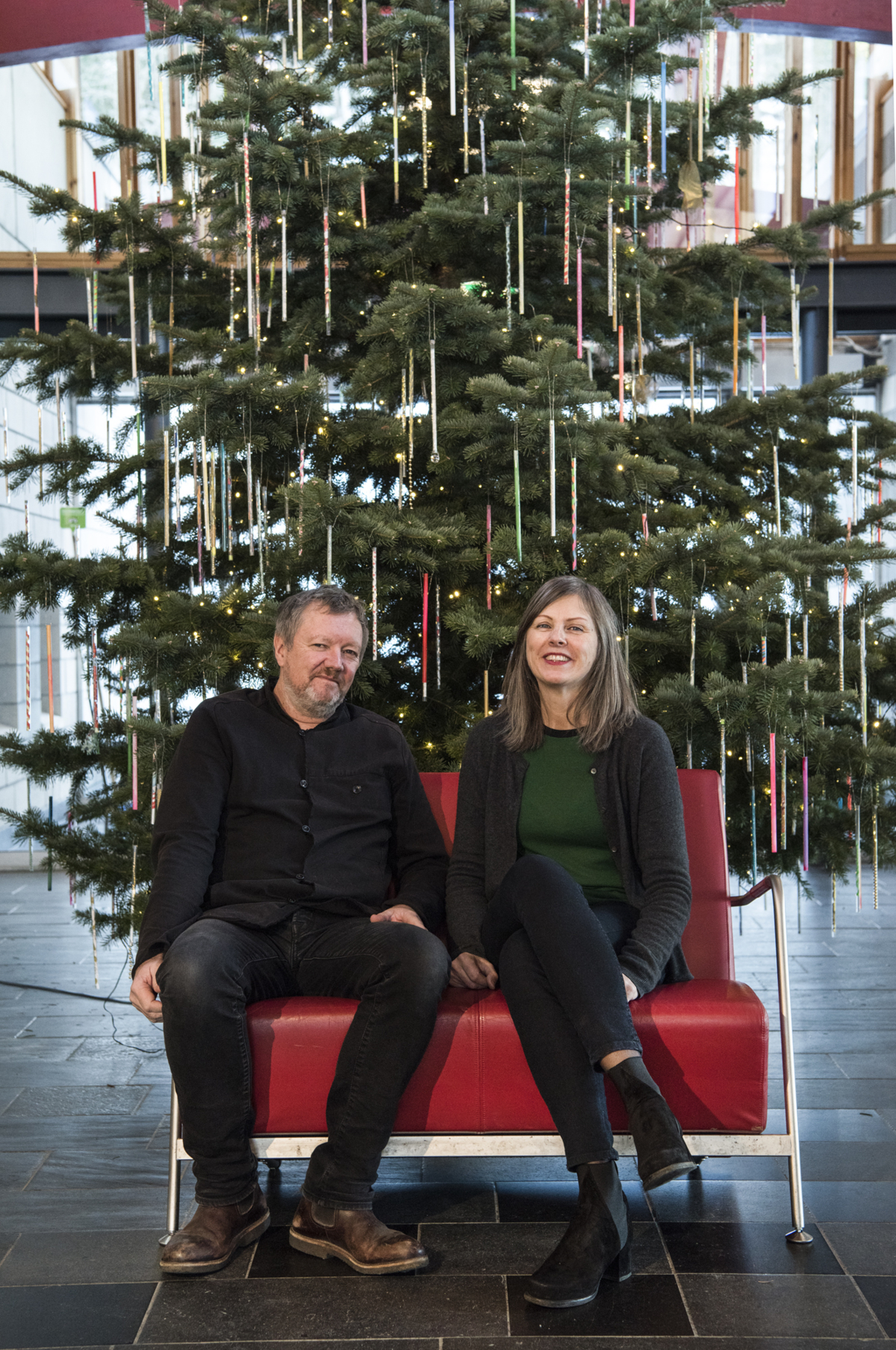 Kjetil Trædahl Thorsen og Jorunn Sannes fra Snøhetta i en rød stol foran et pyntet juletre.