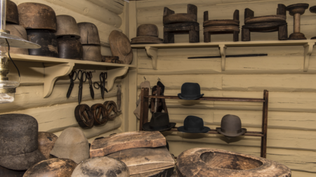Hattemaker-verksted med sakser, former i tre, annet utstyr og filthatter. I friluftsmuseet Maihaugen på Lillehammer.