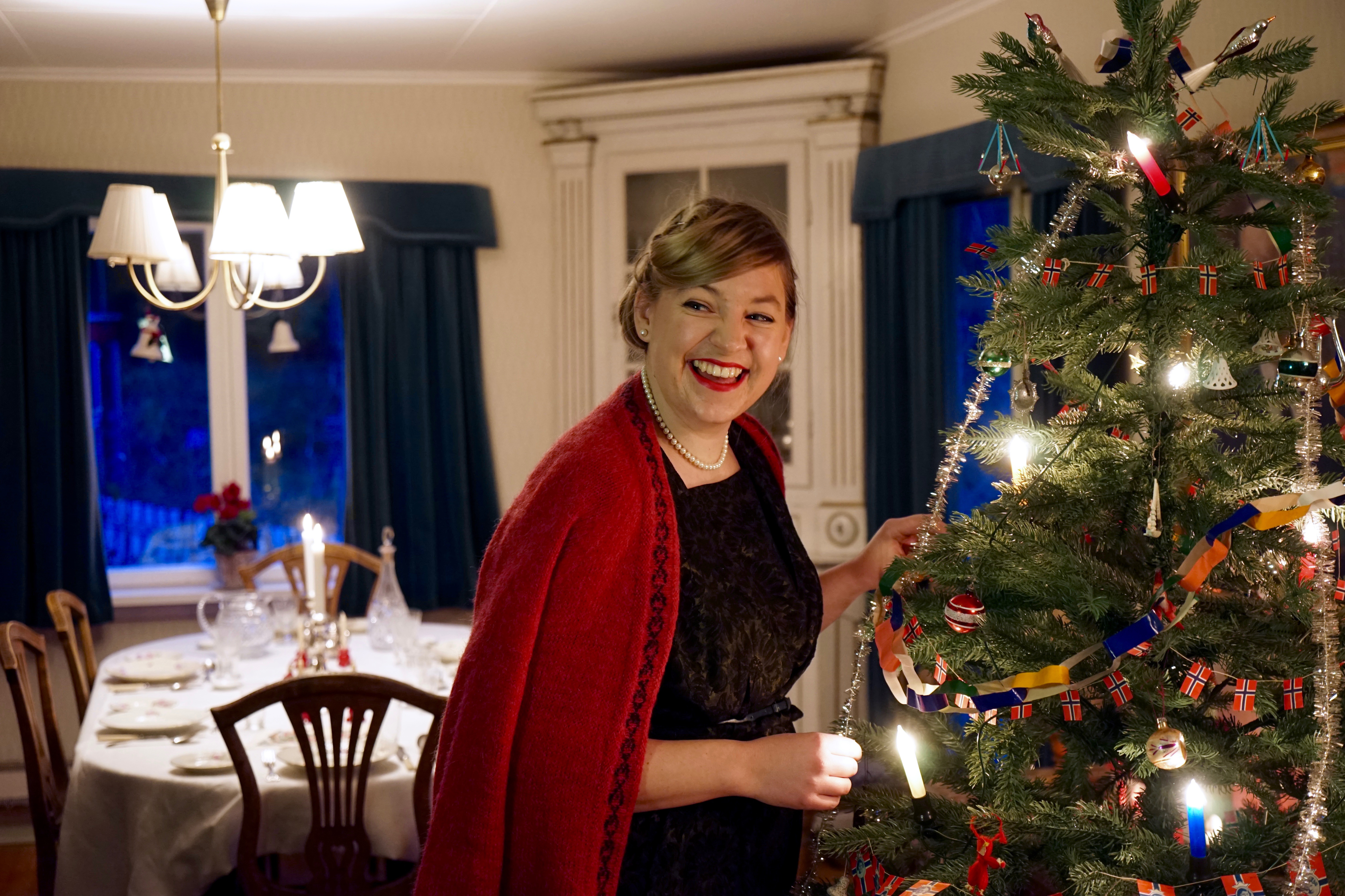 Kvinne i 1950-talls juleantrekk pynter juletreet.