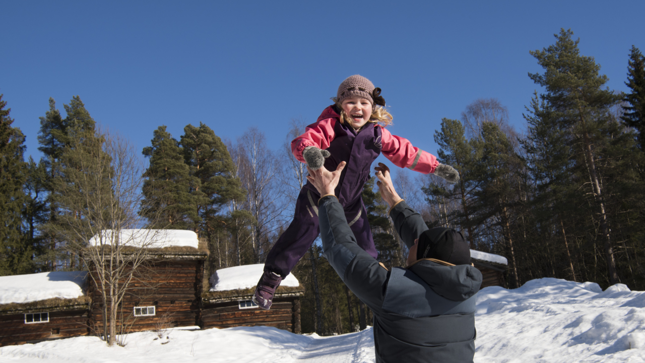 Far kaster jente i lufta. Foto: Camilla Damgård / Maihaugen